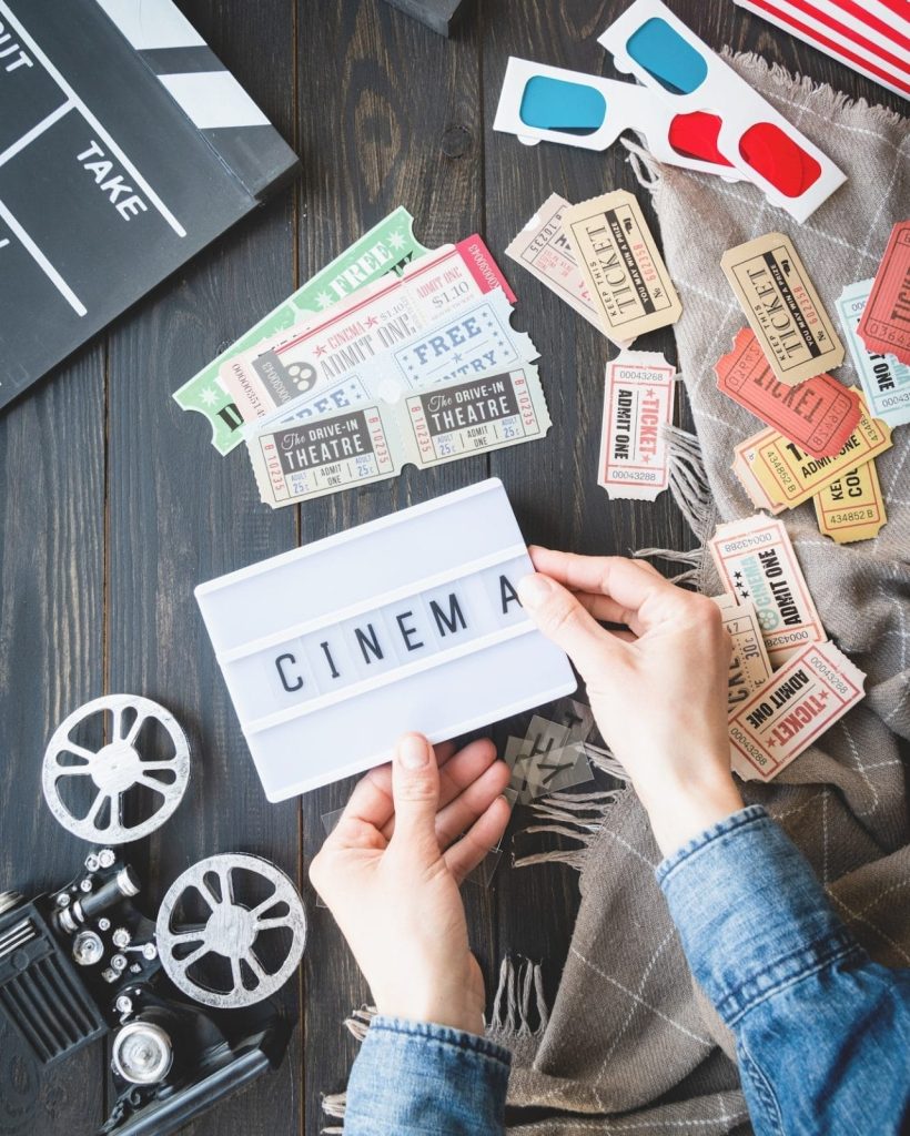 Old school film reel projector, lightbox with word Cinema, clapper board, tickets